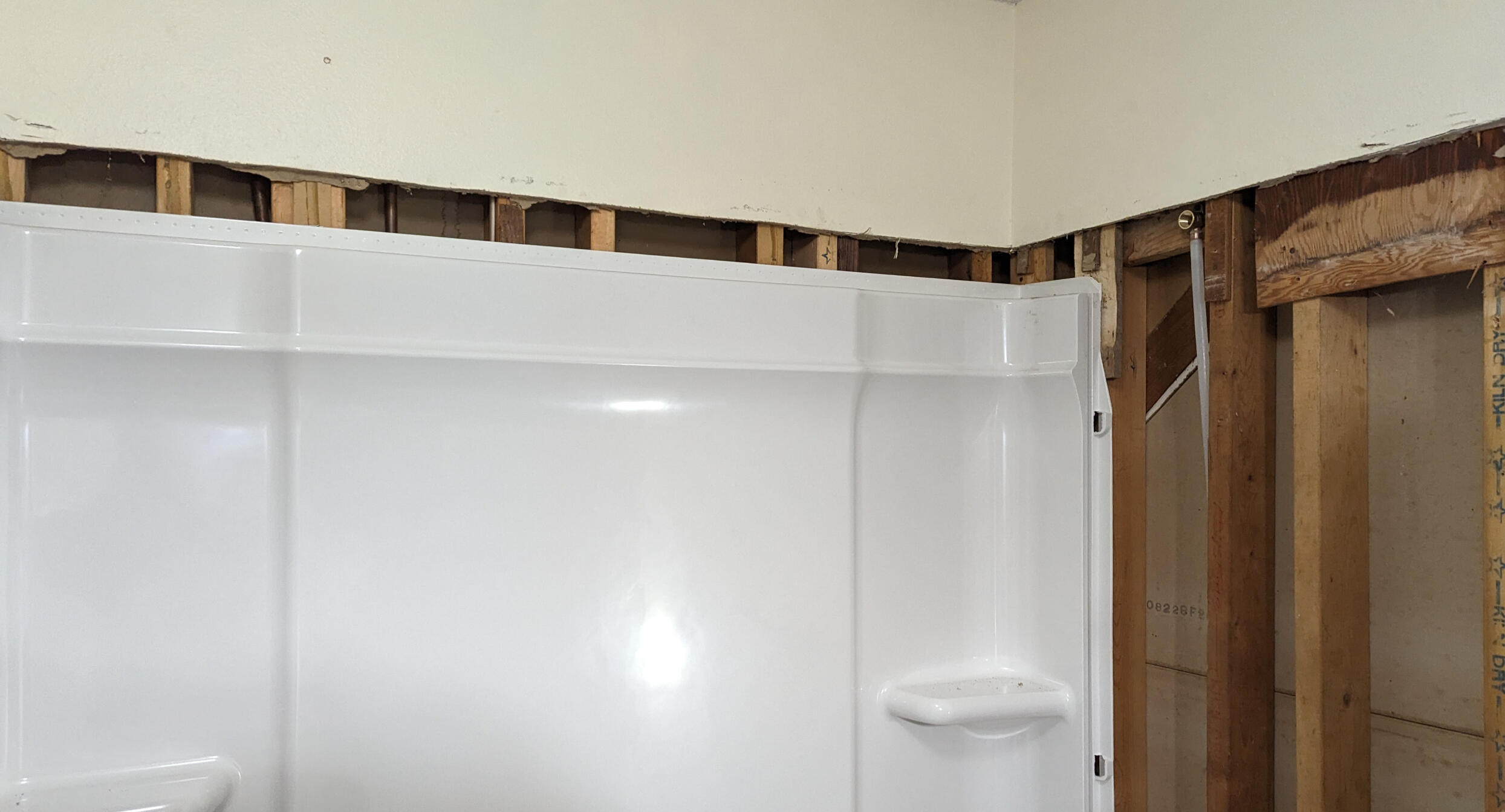 Partially installed bathroom tub - Third Day Plumbing Des Moines Iowa A partially installed bathroom tub surround with exposed wall studs above and to the side, showing an unfinished renovation.